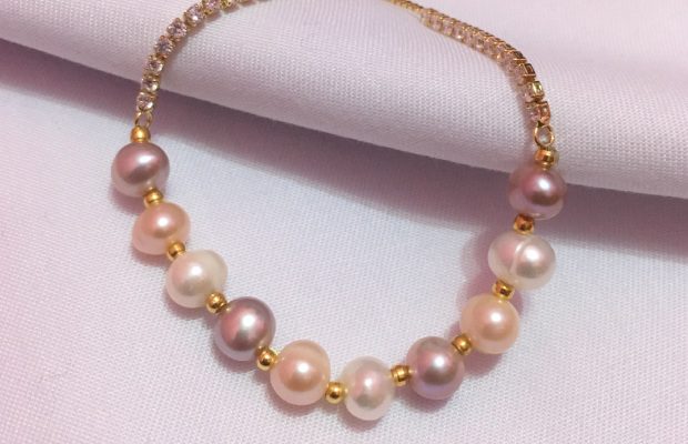 A necklace with pearls on it is laying down.